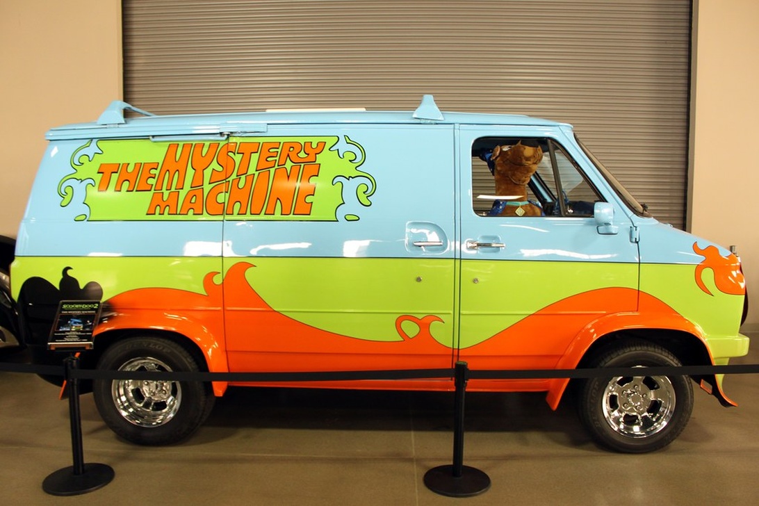 En replika av 'Mystery Machine'-varebilen, kjent fra Scooby-Doo, med sitt karakteristiske blå, grønne og oransje fargeskjema.